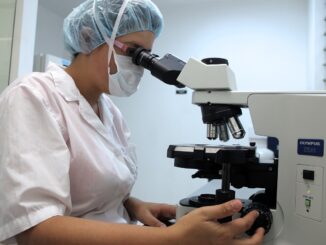 Une chercheuse regardant dans un microscope dans un laboratoire.