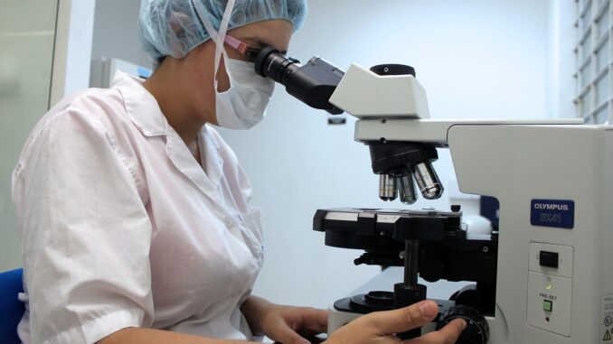Une chercheuse regardant dans un microscope dans un laboratoire.